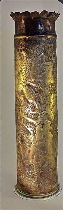 A jubilant Poilu is carried over a comrade's shoulder and pointing towards a Gallic Rooster perched on a 75 Field gun