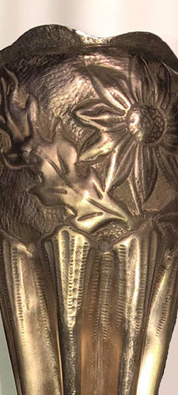 Detail of the bulbous top and the indentation work under the embossed daisies.