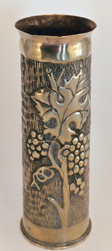 Shell embossed with grapes on vine&nbsp; with rows of vertical indentations as background.