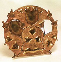 Round brass sheet cut-out with three openings among a garland of ivy. Souvenir&nbsp; and 1919 engraved on one of the garland loop.