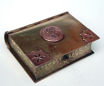 Jewel box in the shape of a book. Lid with center medallion in copper. Two edges&nbsp; with&nbsp; copper&nbsp; flower.